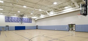 Modern new community gym space with basketball hoops and large floor space.