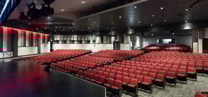 Modern high school auditorium with theater style seating and modern architecture style